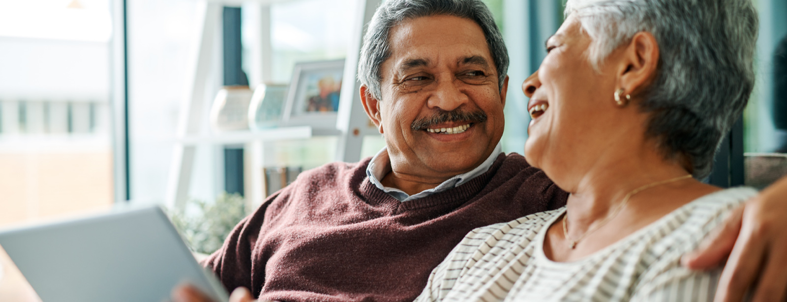 Mature hispanic couple looking at each other while using a tablet device